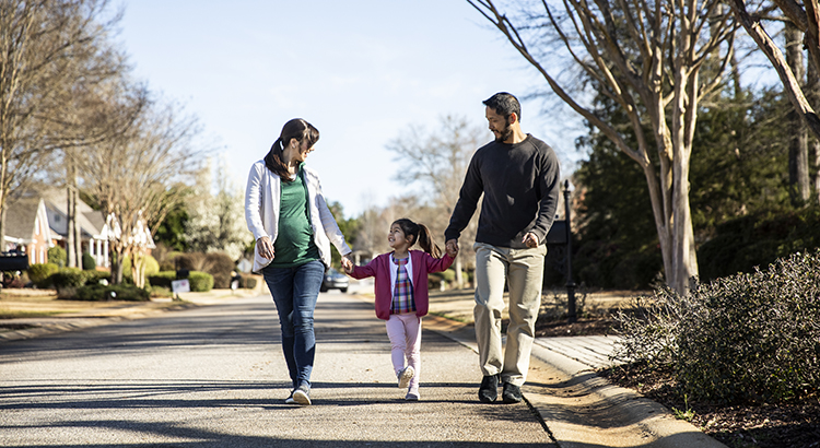 Family of three walking in suburban neighborhood