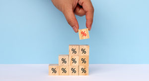 Hands Stacking Percent Signs on Wood Toy Block